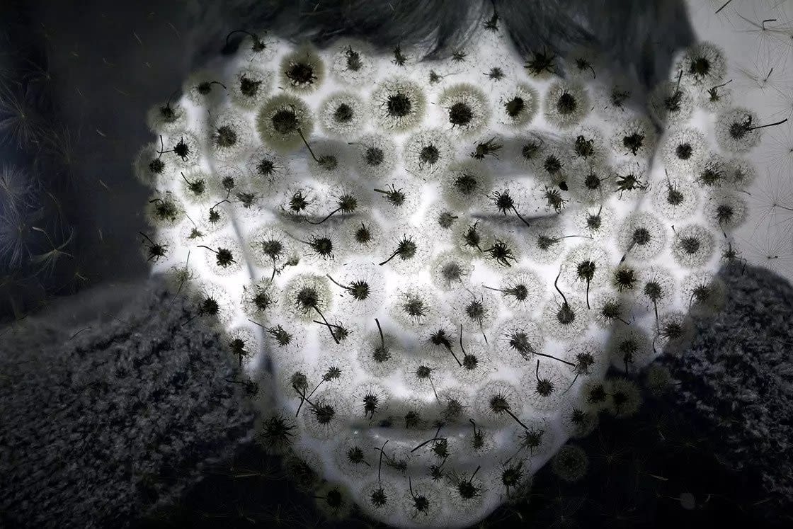 Black and white photo, face of a child covering their ears made by using images of dandelions