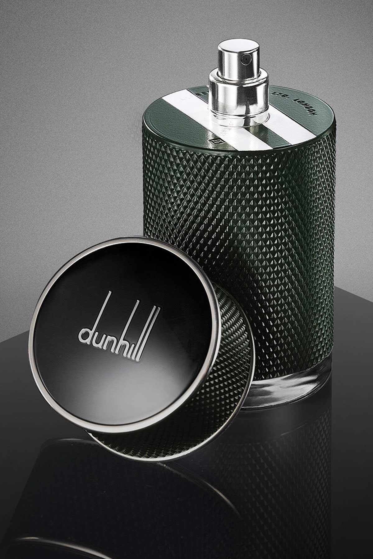 A full frame view of a green Dunhill Icon Racing fragrance bottle with the cap off showing the two white racing stripes.