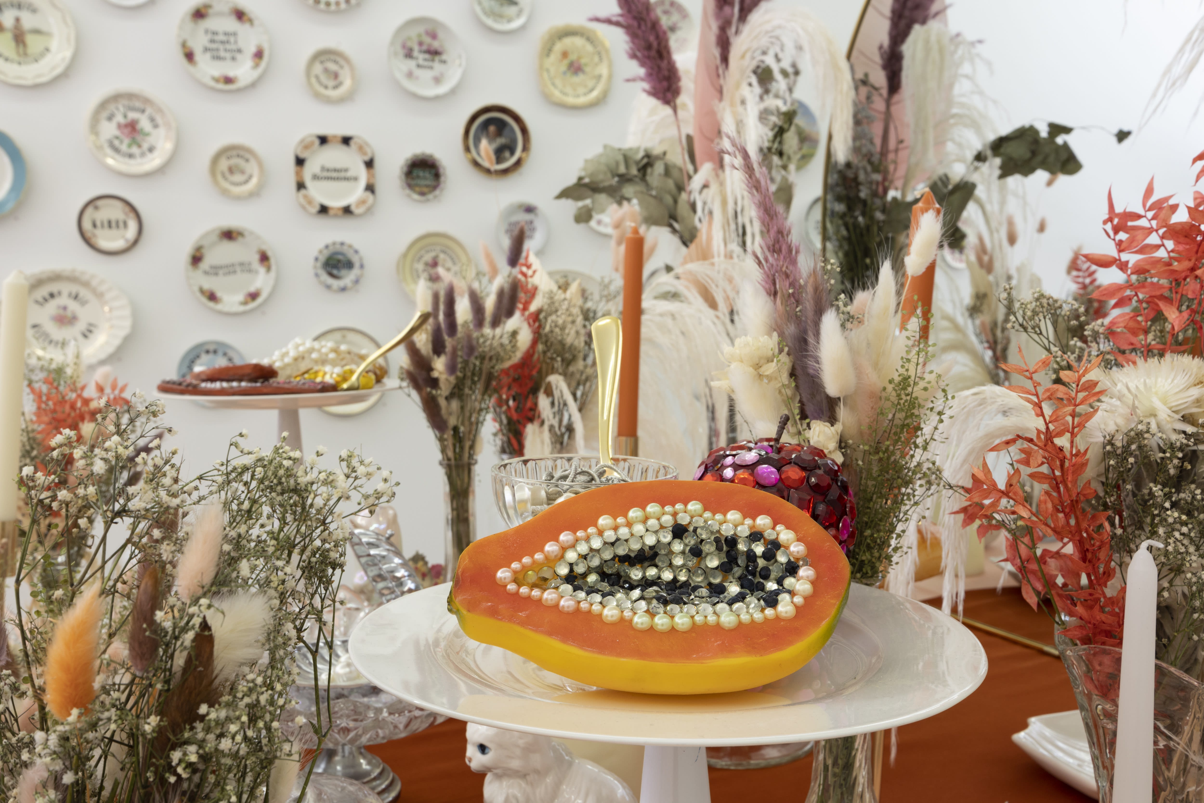Photo of bejeweled fruit on a table with plates in the background by Marie Claude Marquis