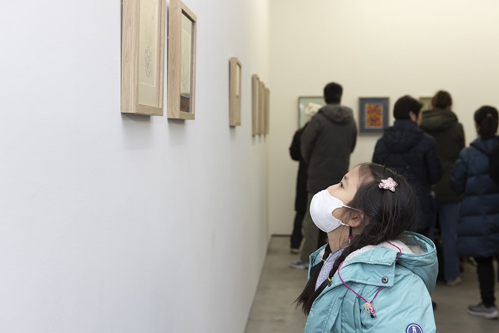 child looking at drawings by Felicia Chiao