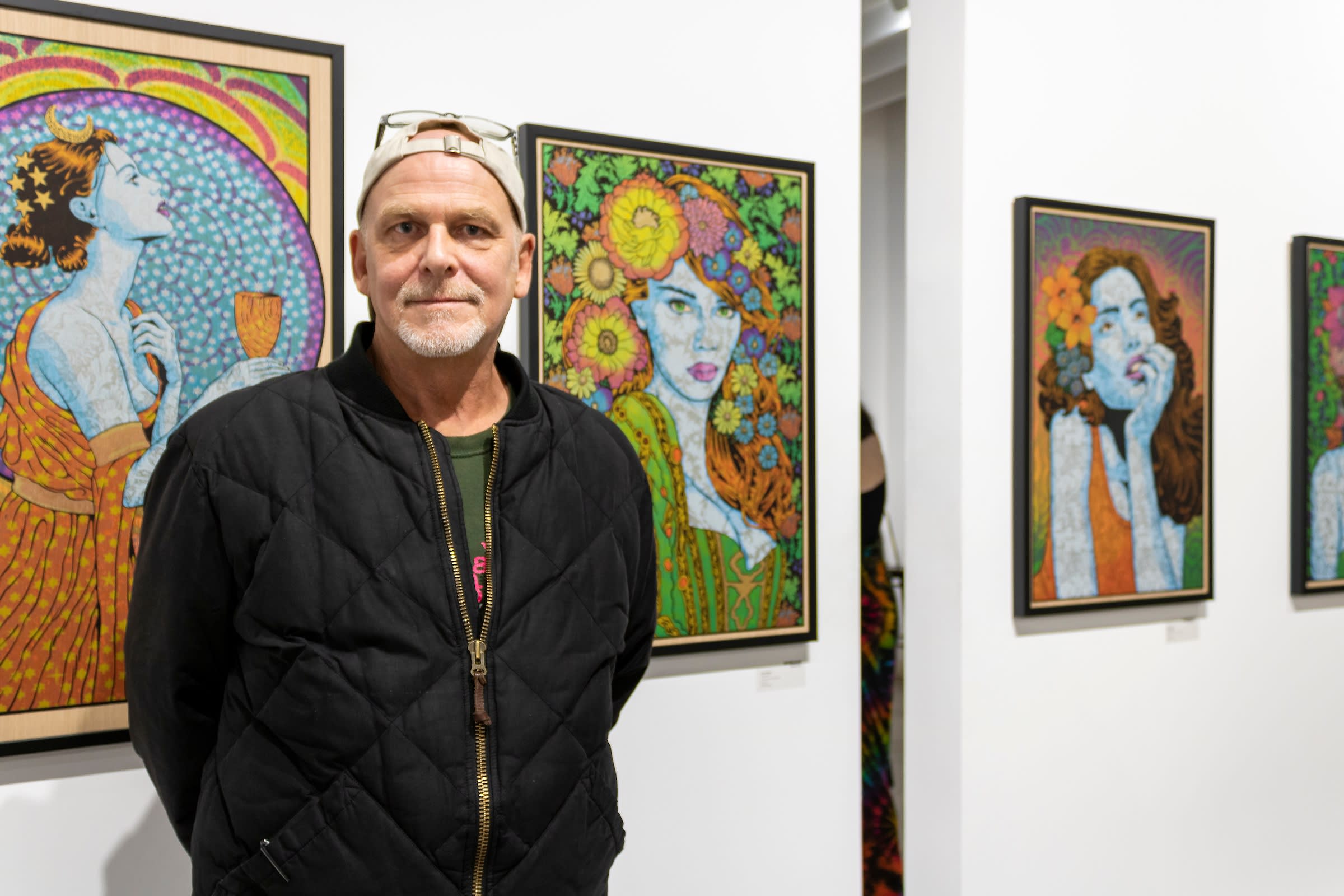 Artist Chuck Sperry standing in front of his artwork.