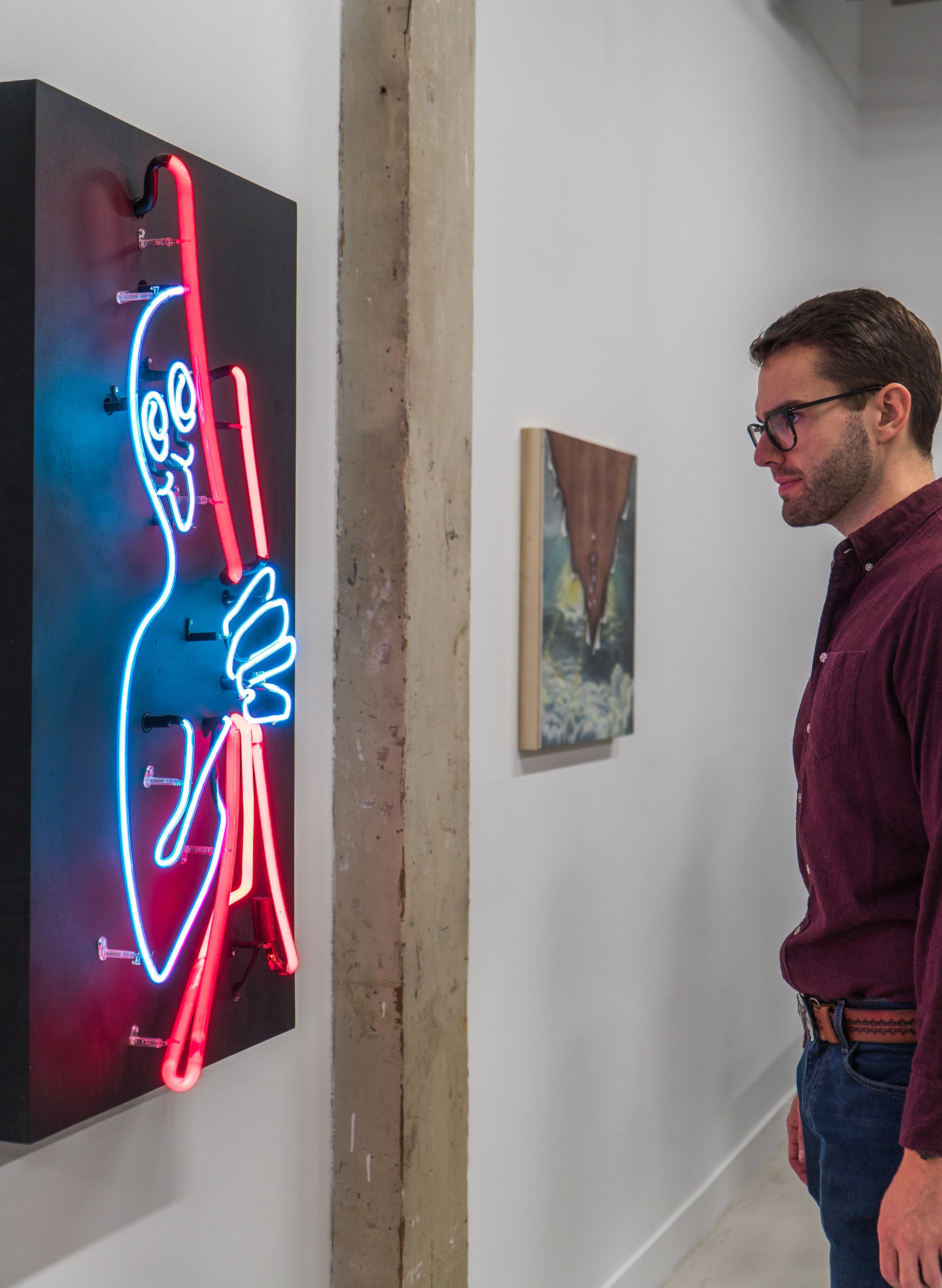 photo of a man looking at Anika River's neon artwork