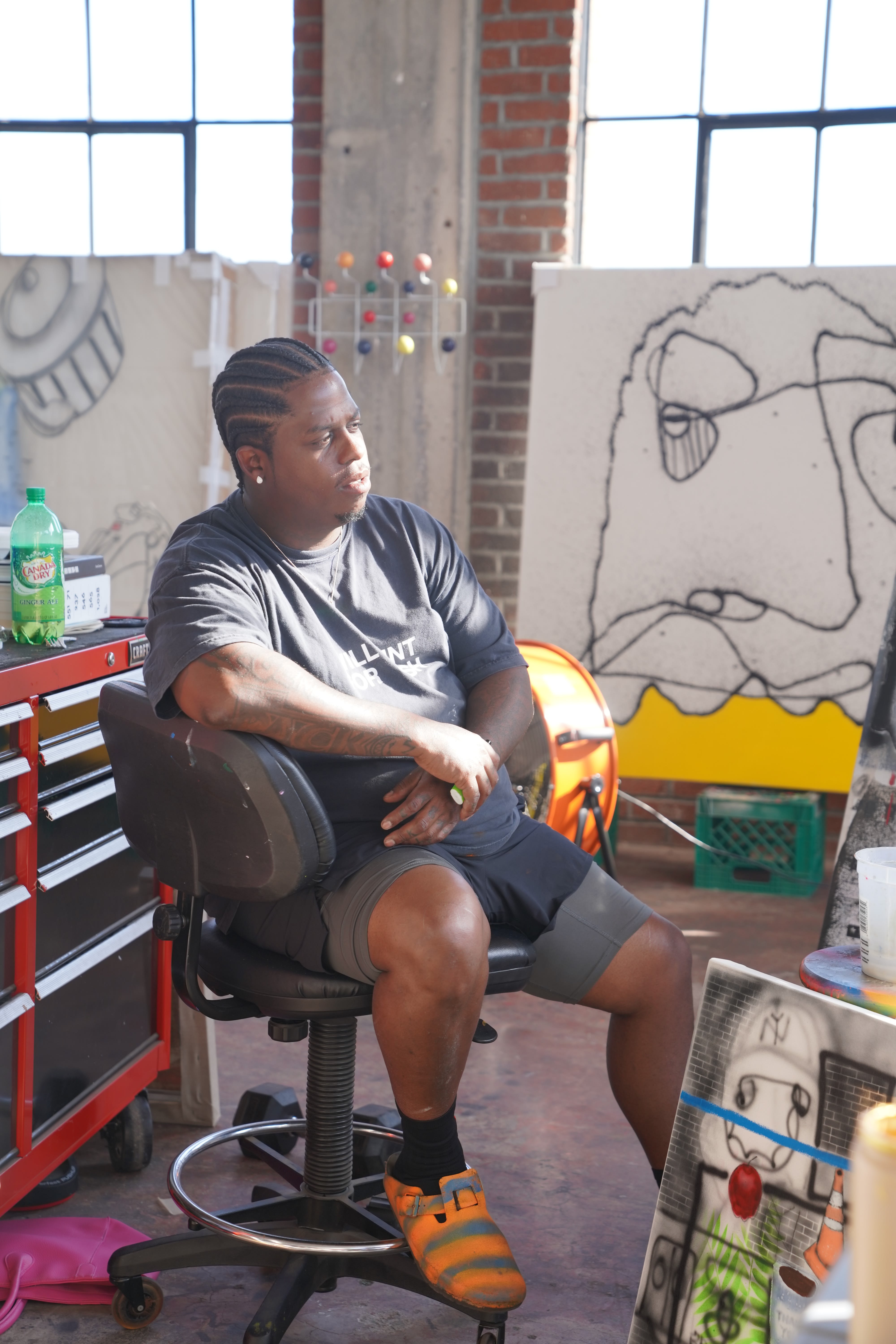 photo of the artist Jahlil Nzinga sitting in his studio