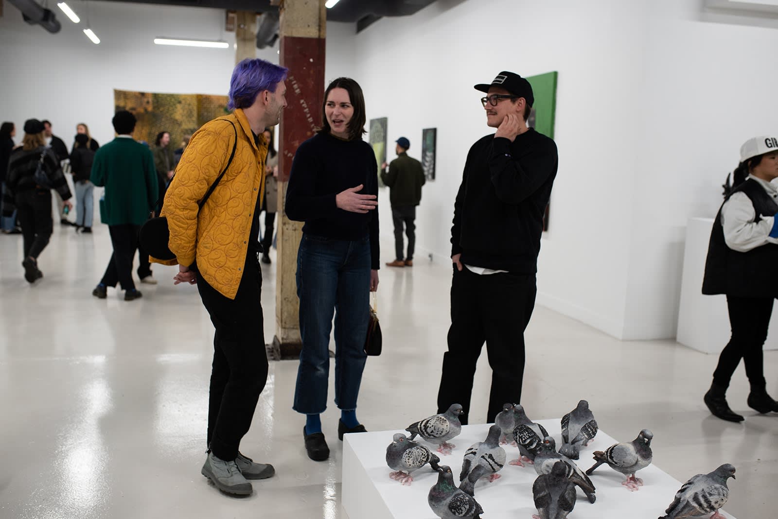 photograph of people inside the gallery surrounded by paintings and artwork