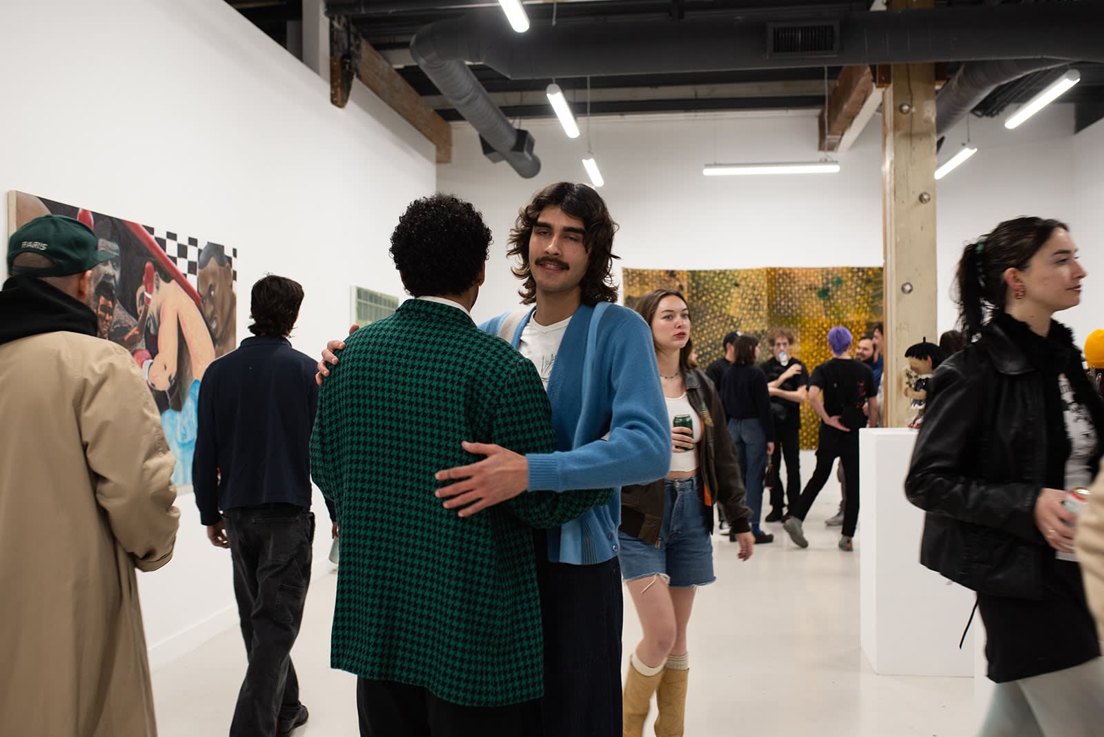 photograph of people inside the gallery surrounded by paintings and artwork