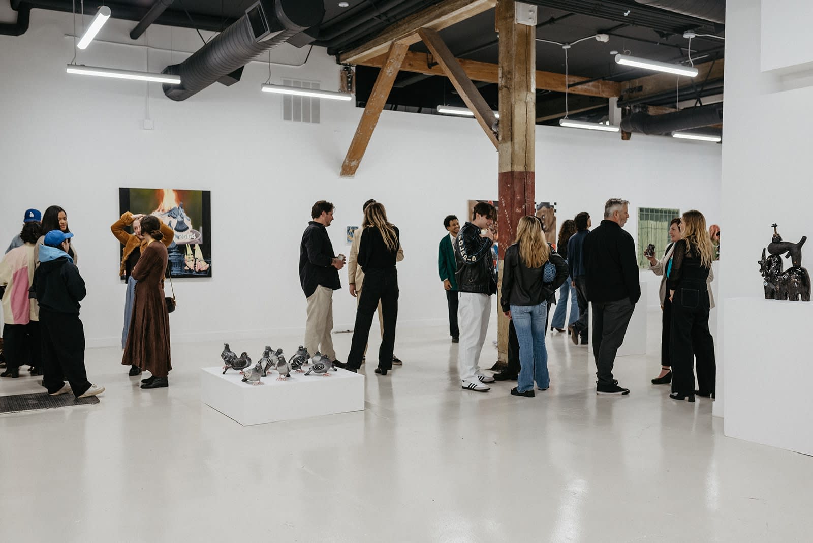 photograph of people inside the gallery surrounded by paintings and artwork