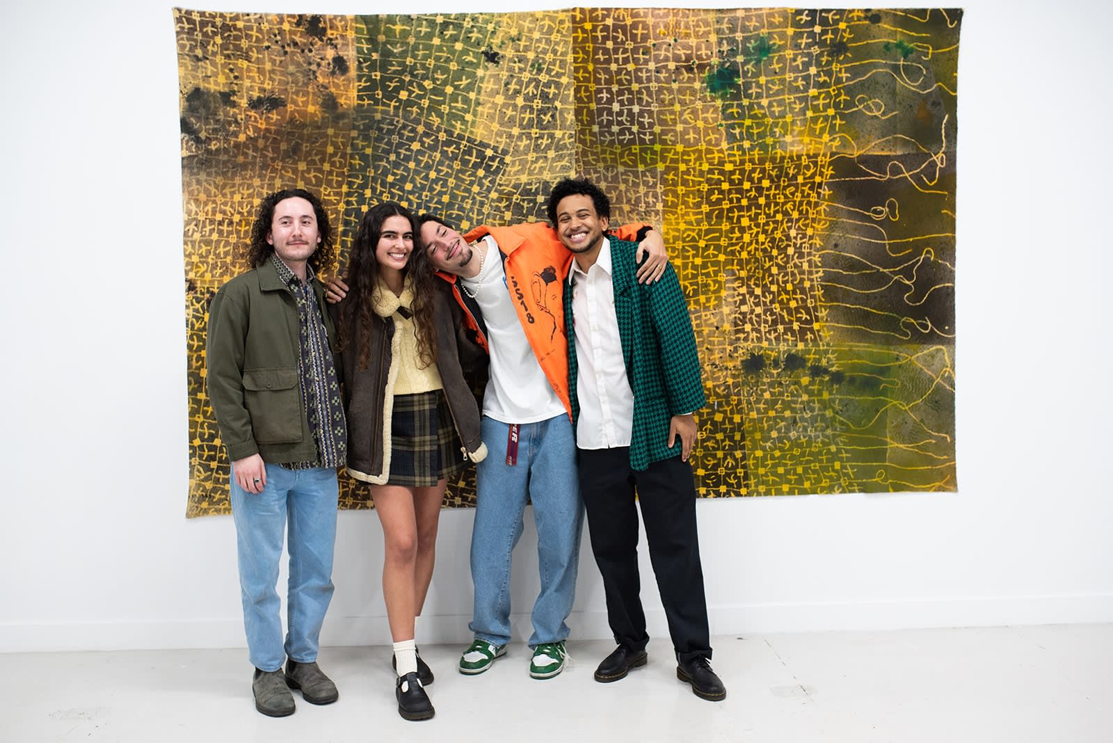 photo of the artists posing together in front of a large artwork