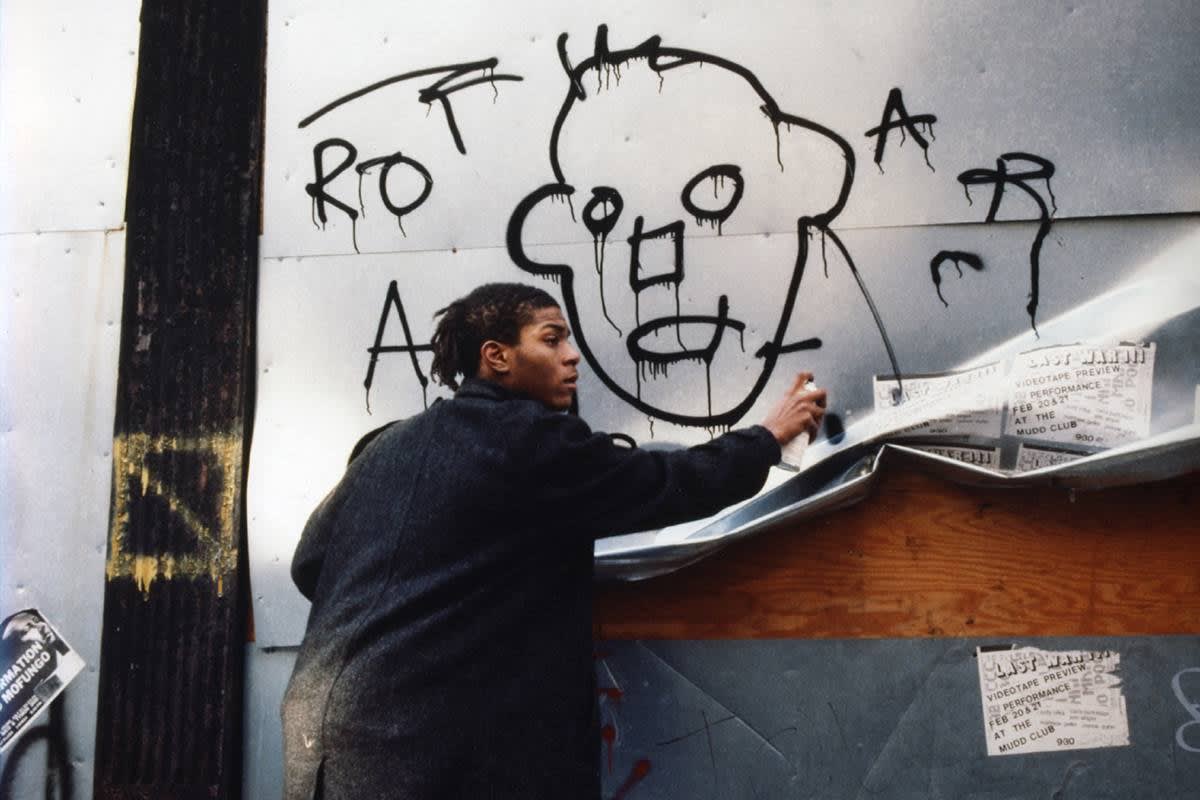 Jean Michael Basquiat spray painting walls during his early days as an Urban artist.