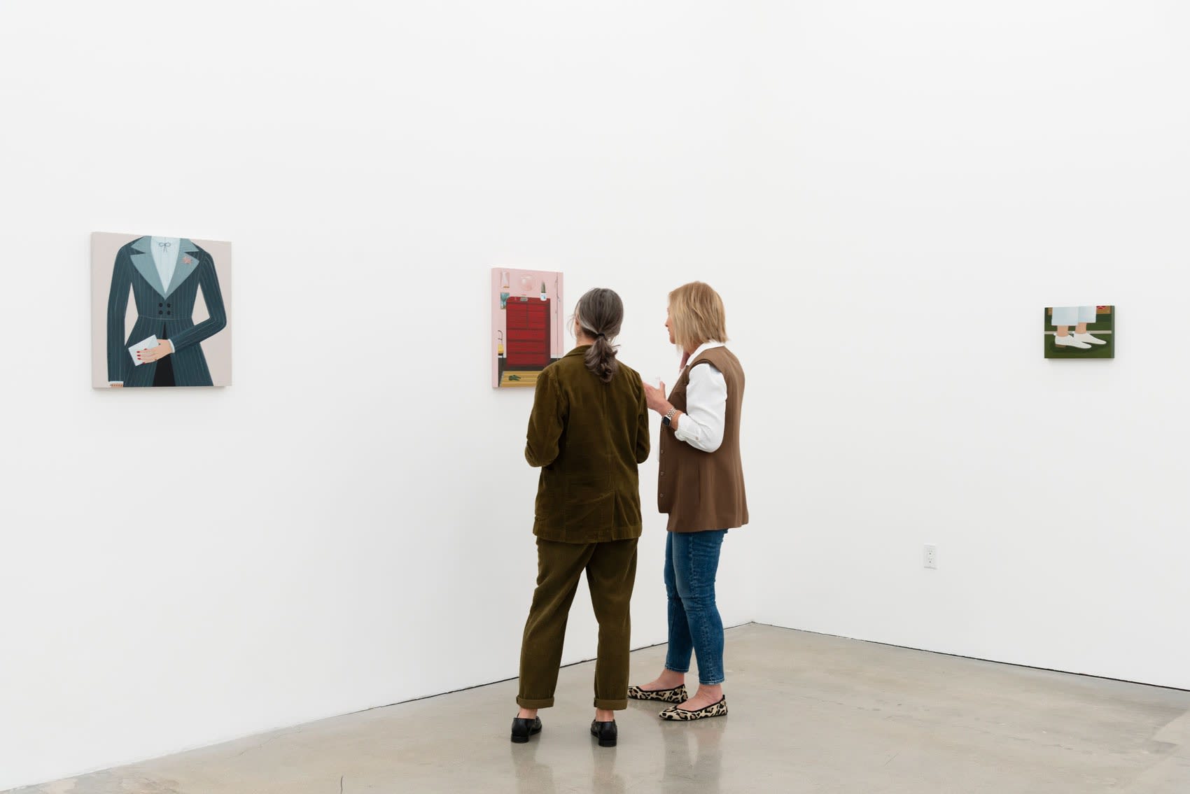 Two people look at Angela Burson's painting in an art gallery with white walls. 