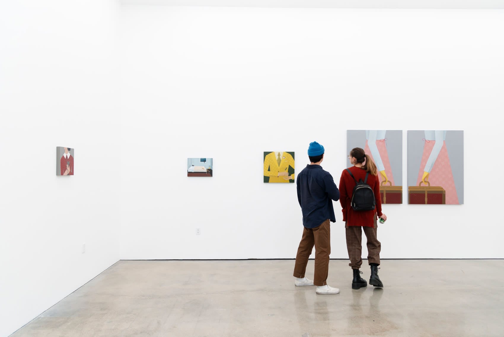 Two people look at Angela Burson's painting in an art gallery with white walls. Burson's paintings are bright, flat, and illustrative depictions of headless figures in motion, wearing classic patterns like polka dot or houndstooth. 