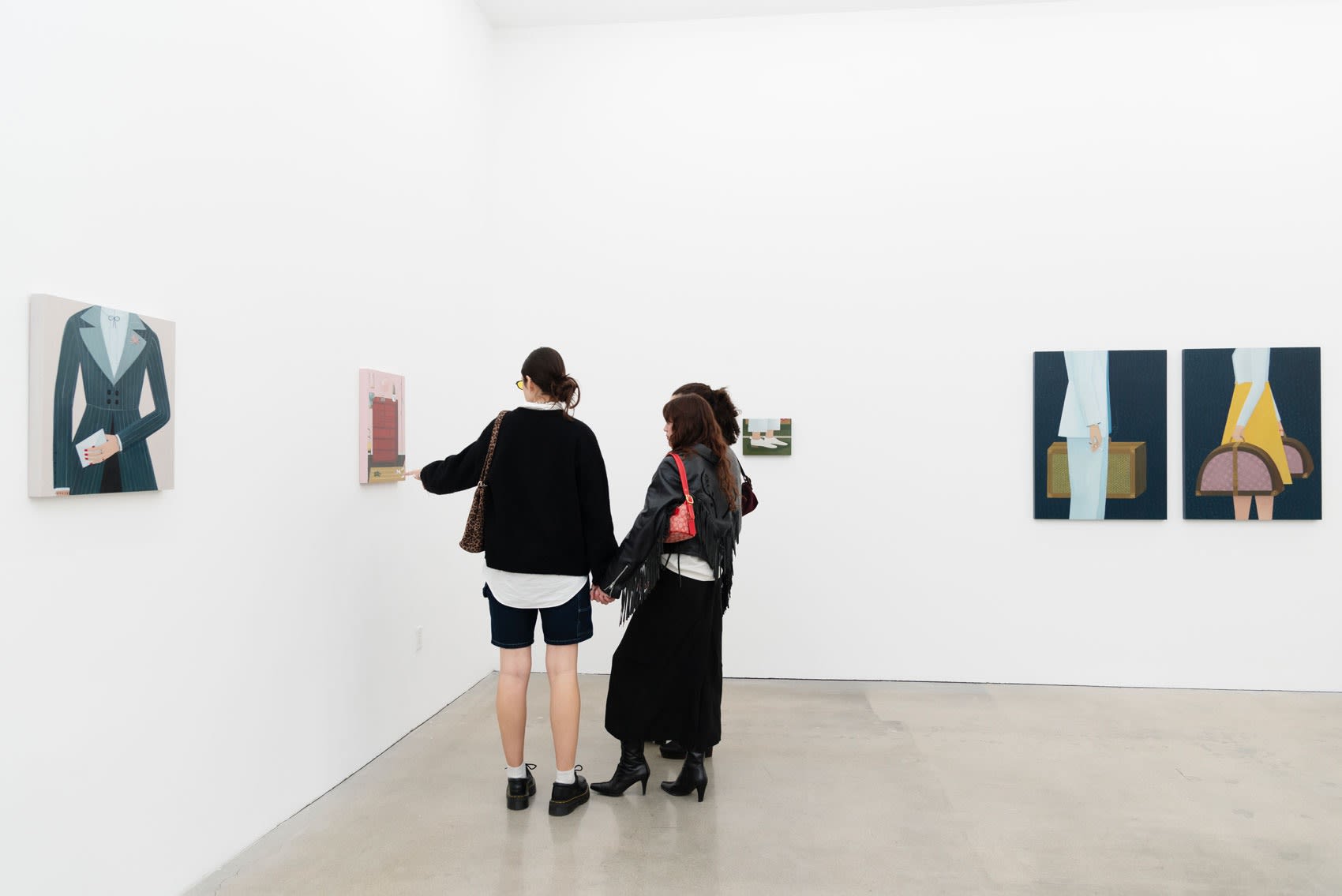 Two people look at Angela Burson's painting in an art gallery with white walls. 