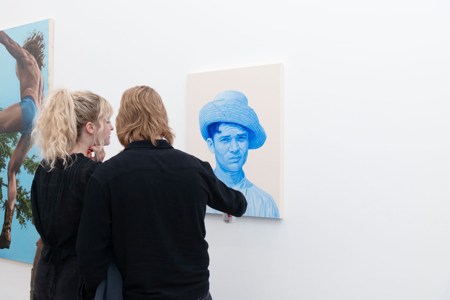 two people looking at a painting of a man on the wall