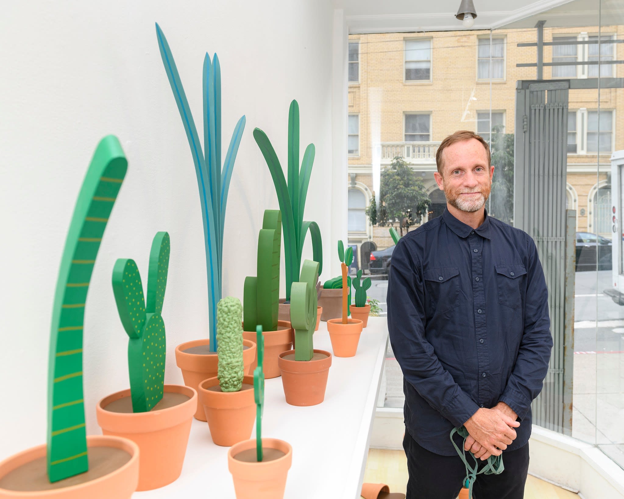 photo of artist Jeff Canham standing in front of his wooden plant sculptures