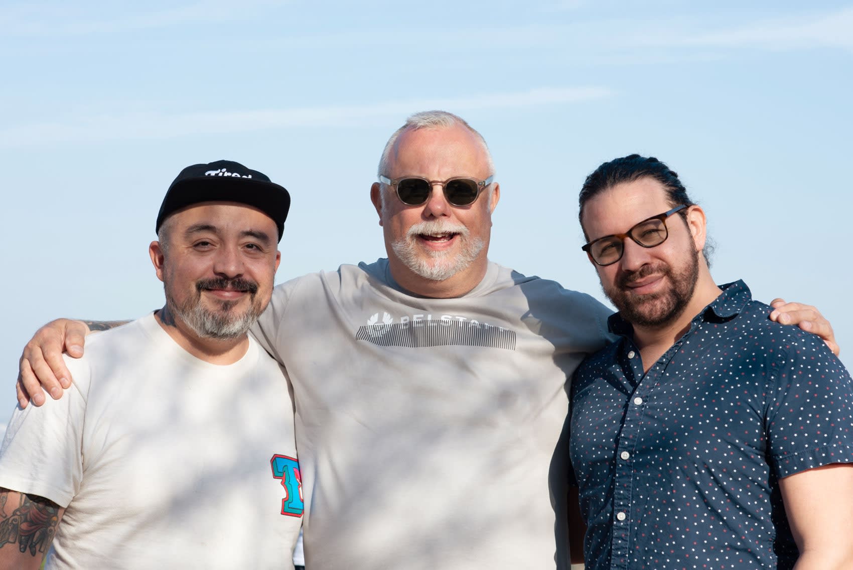 An image of three men with a blue sky background: Carlos Rodriguez, Andrew Durrant, and Jean Paul Mallozzi