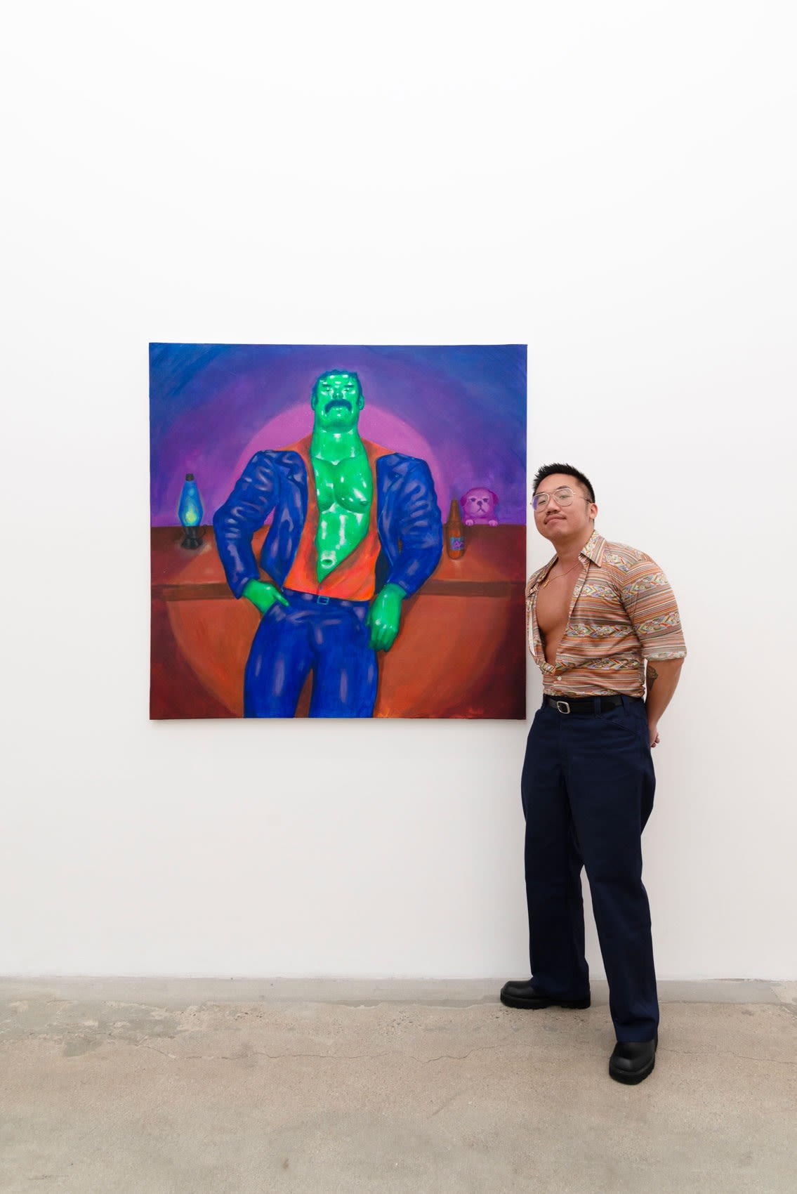 artist Justin Yoon with his large, vertically oriented painting of a muscular green man