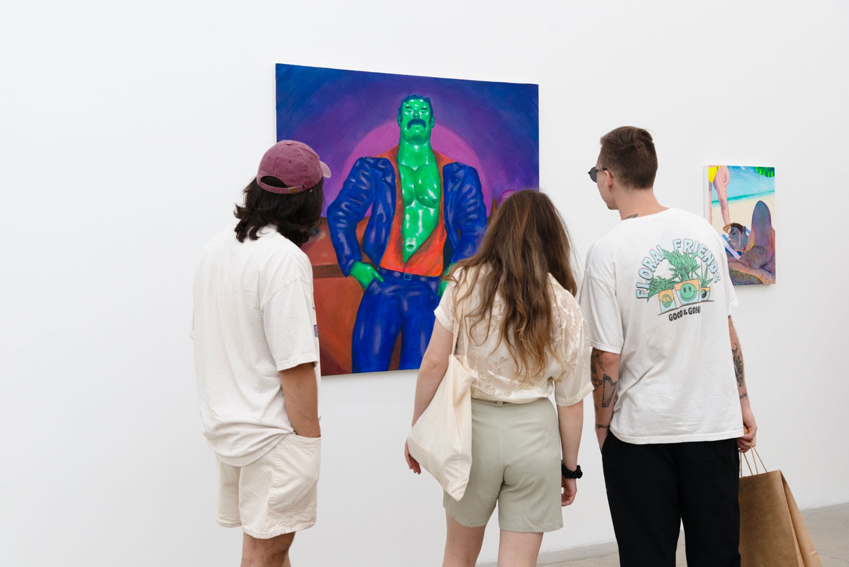 Three young people look at a bright blue, green, and purple painting in a gallery.