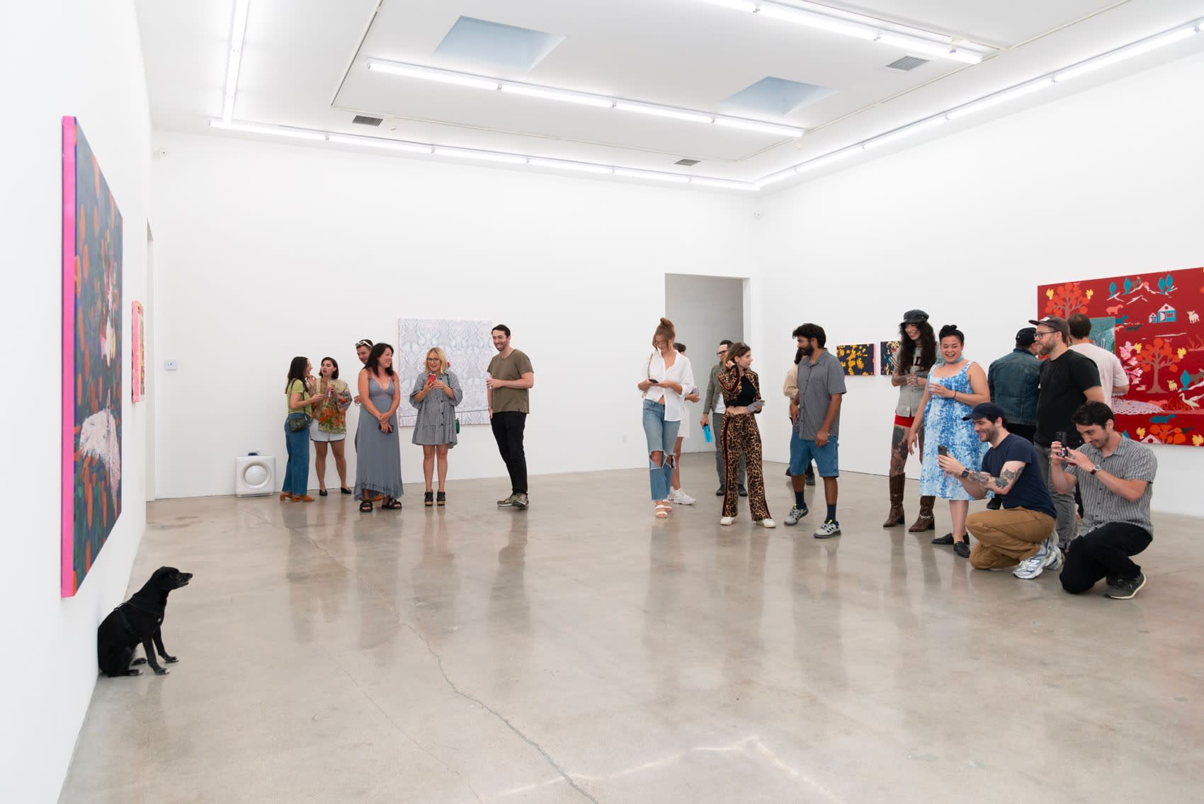 Meera, a small black dog with nervous tendencies, poses in front of a large painting while a crowd of people take her photo.