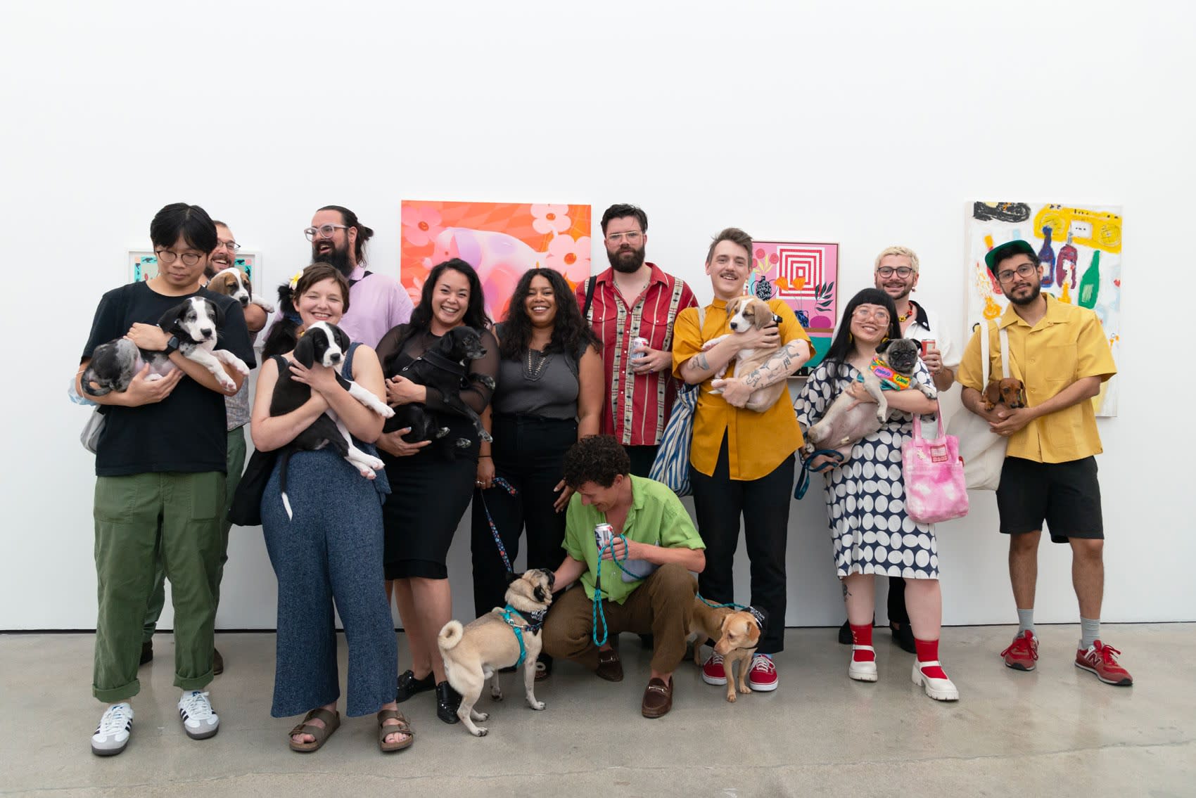 Artists and Hashimoto Contemporary staff hold dogs in a white cube gallery in front of paintings