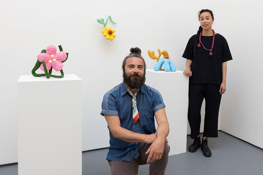 Artist duo CHIAOZZA standing with their work