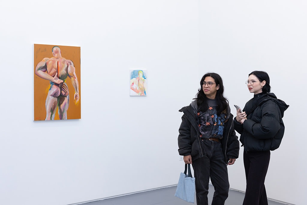 Two people stand in an art gallery looking at the painting and study drawing of 