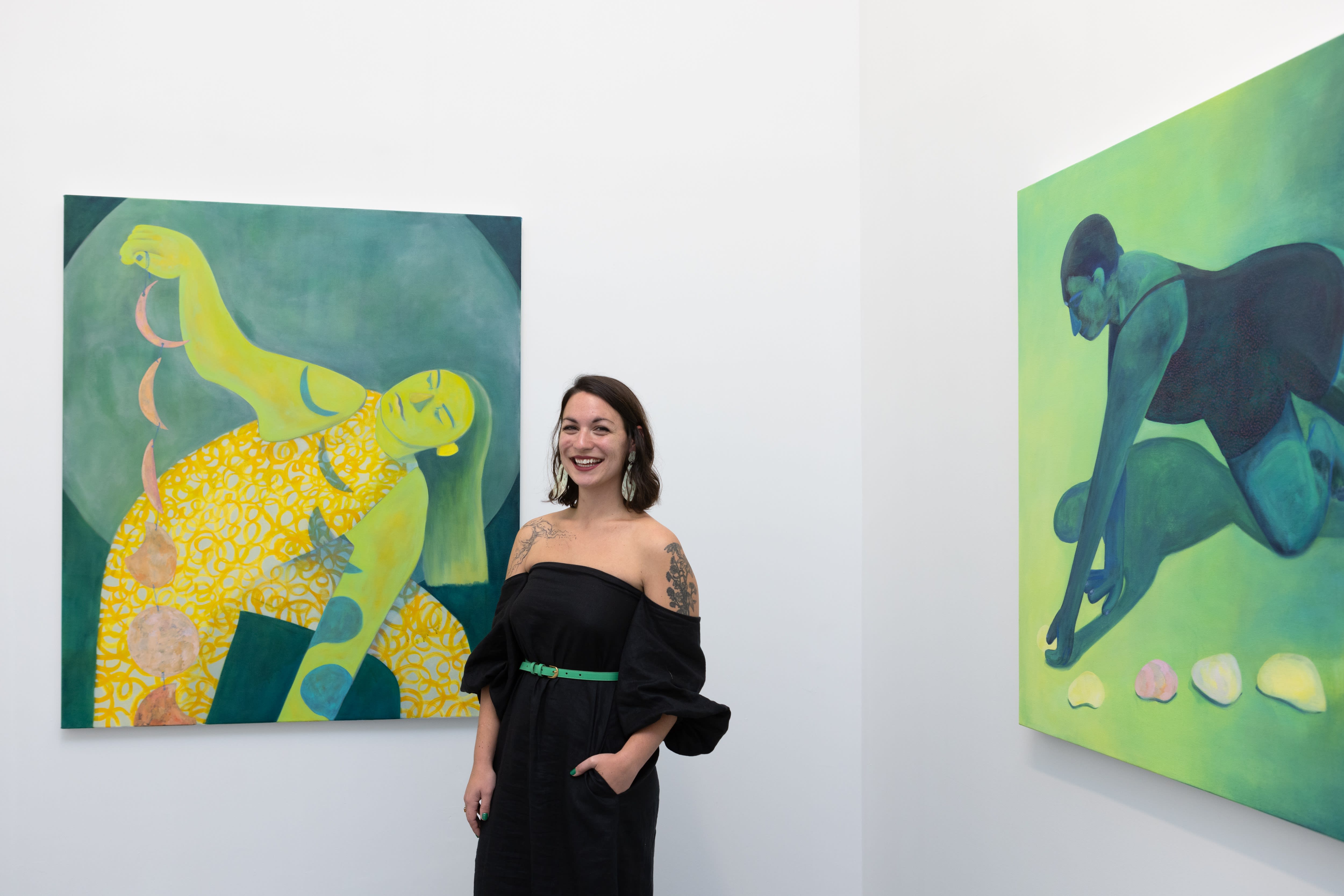 Genevieve Cohn standing in front of two of her paintings