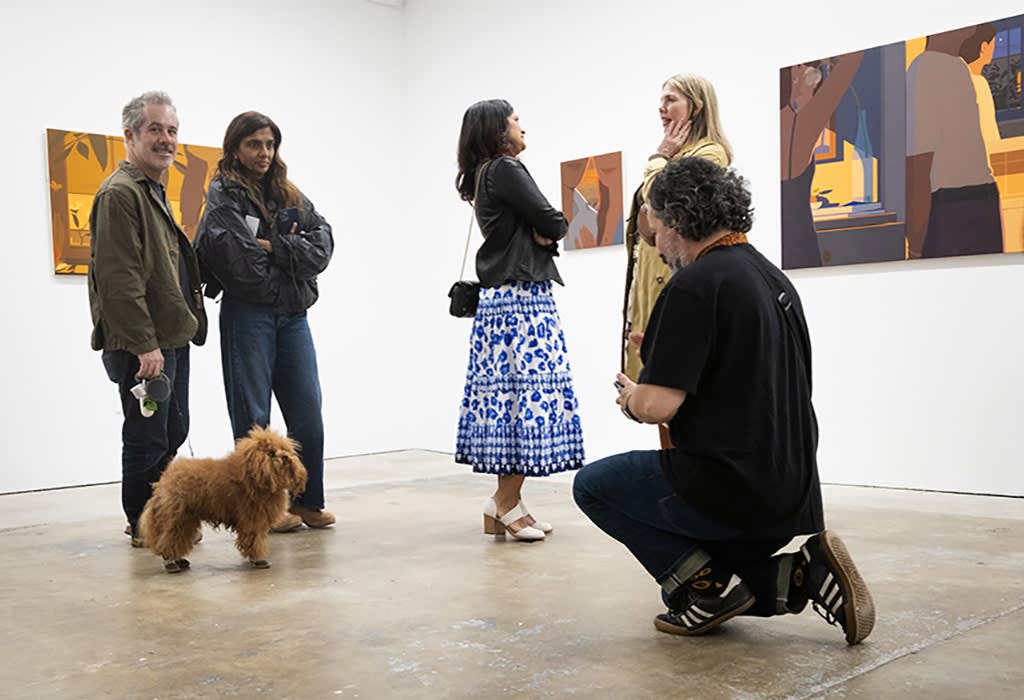 Image of a person squatting down to take a photo of a small brown dog at the opening reception for Adrian Kay Wong at Hashimoto Contemporary, San Francisco