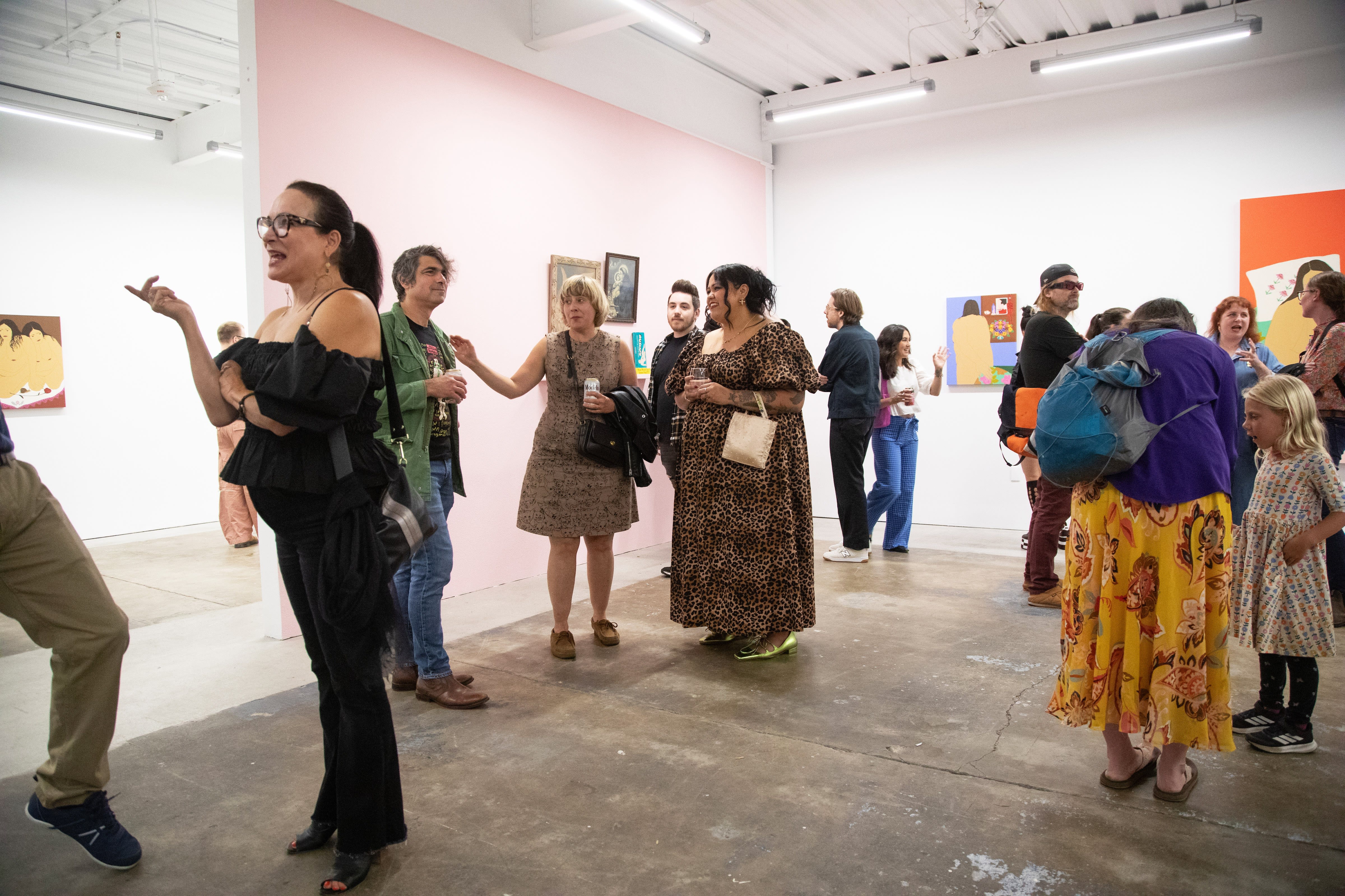 Visitors enjoy the exhibition Amor Secreto by Gina M. Contreras inside a white wall art gallery with low fluorescent lights. 