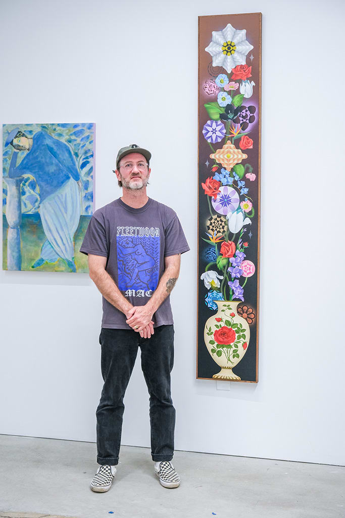 Photo of artist Casey Gray next to his work at the opening reception of 