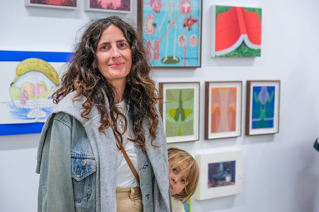 Photo of artist Rachel Kaye next to her work at the opening reception of 