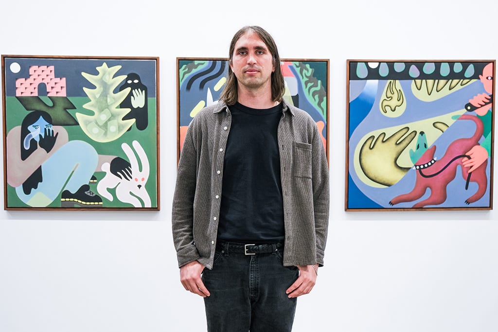 Photo of artist Austin Elfio Montanari next to his work at the opening reception of 