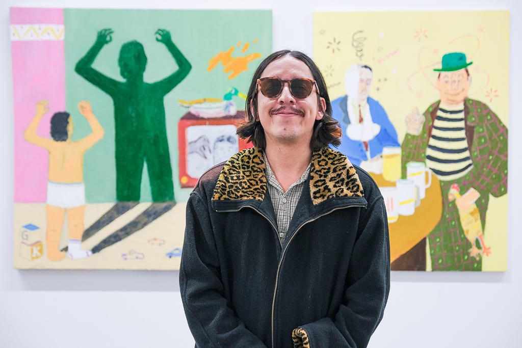 Photo of artist Gabriel Isaac Kasor next to his work at the opening reception of 