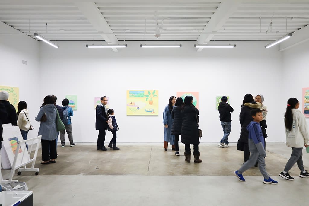 A group of people walk around Danym Kwon's solo exhibition A Soft Day. The gallery has white walls and a concrete floor. 