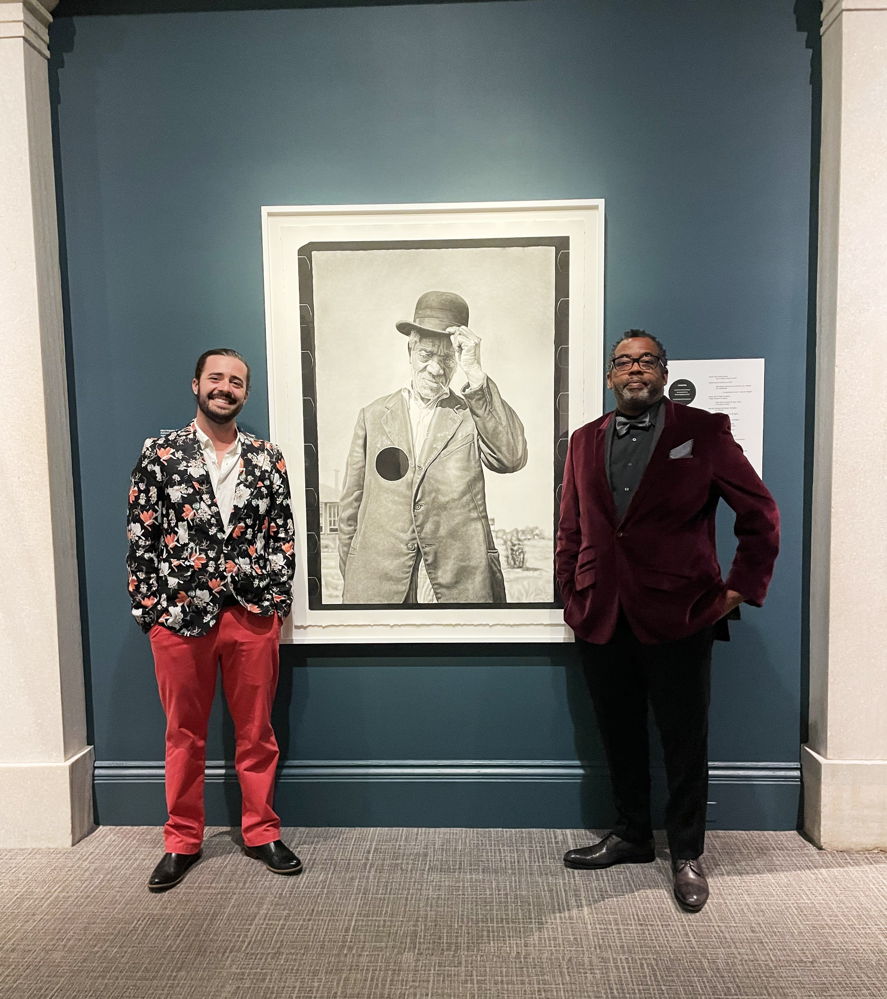 Joel Daniel Phillips standing in front of his graphite drawing with Quraysh Ali Lansana