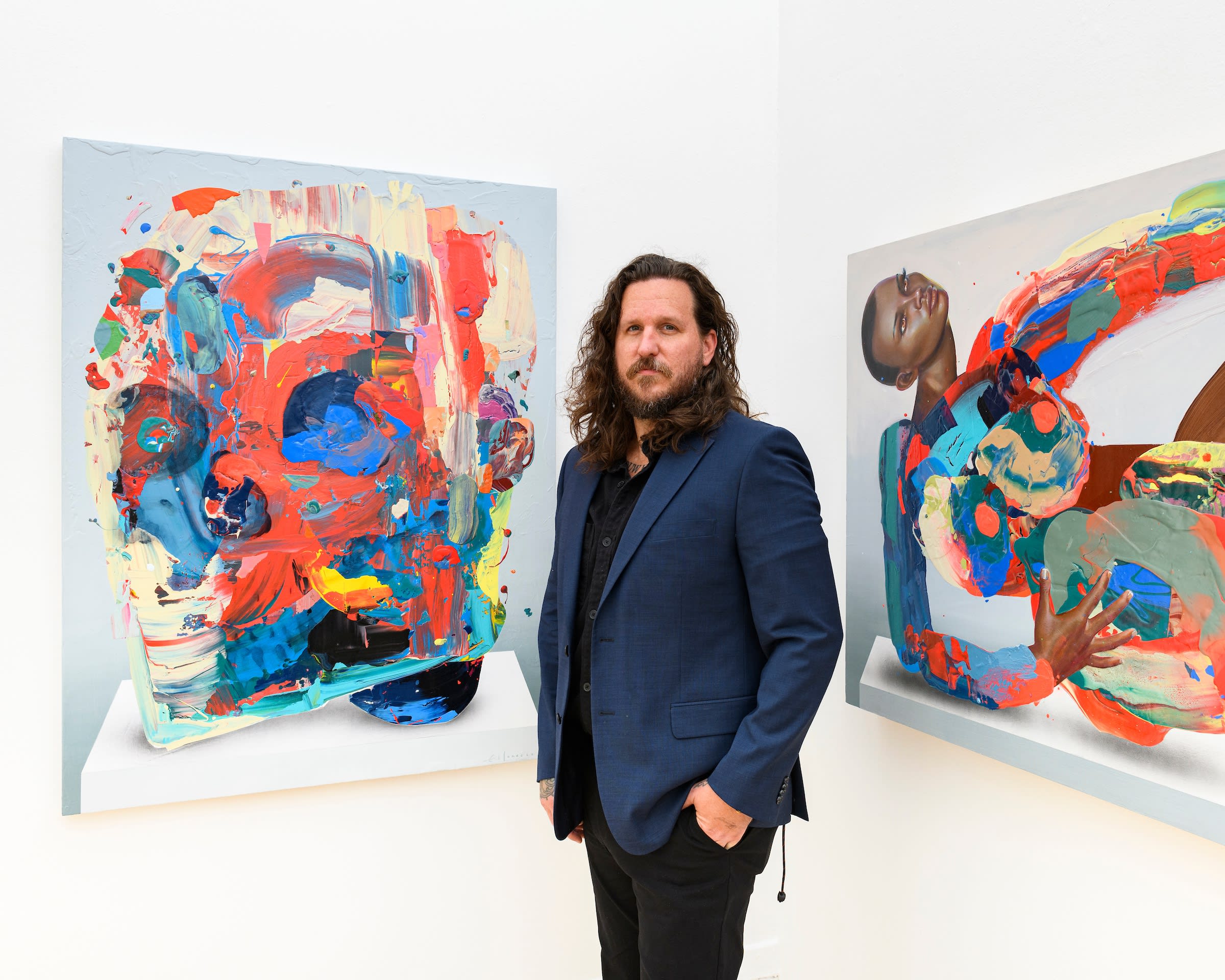 Erik Jones at his solo show standing infront of two pieces 