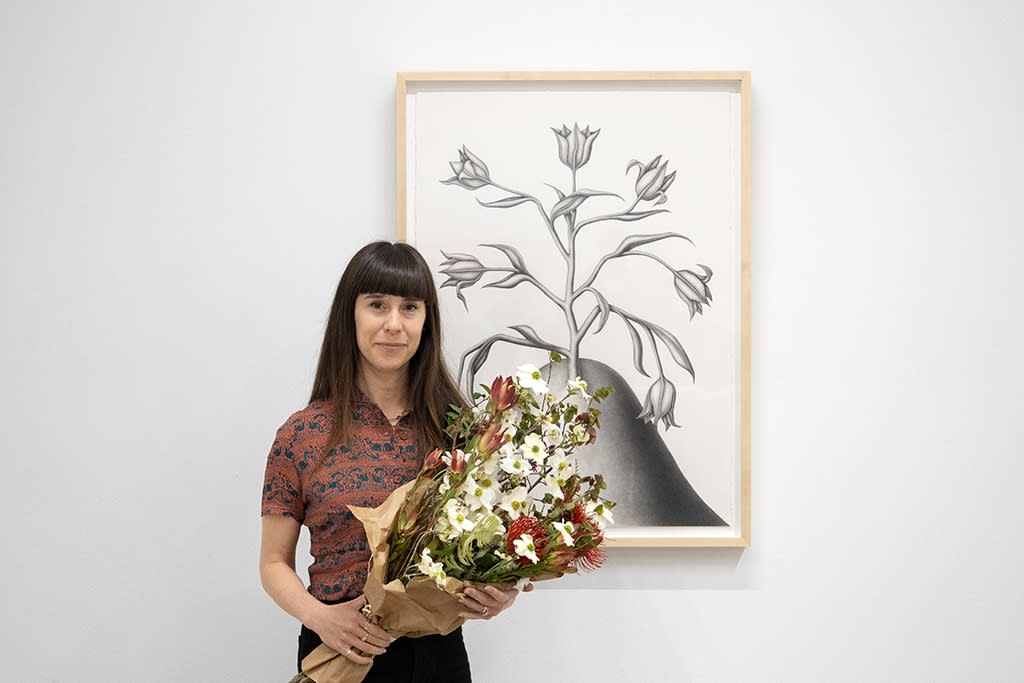 Devra Fox posing in front of her artwork at the opening of her exhibition In Orbit. 