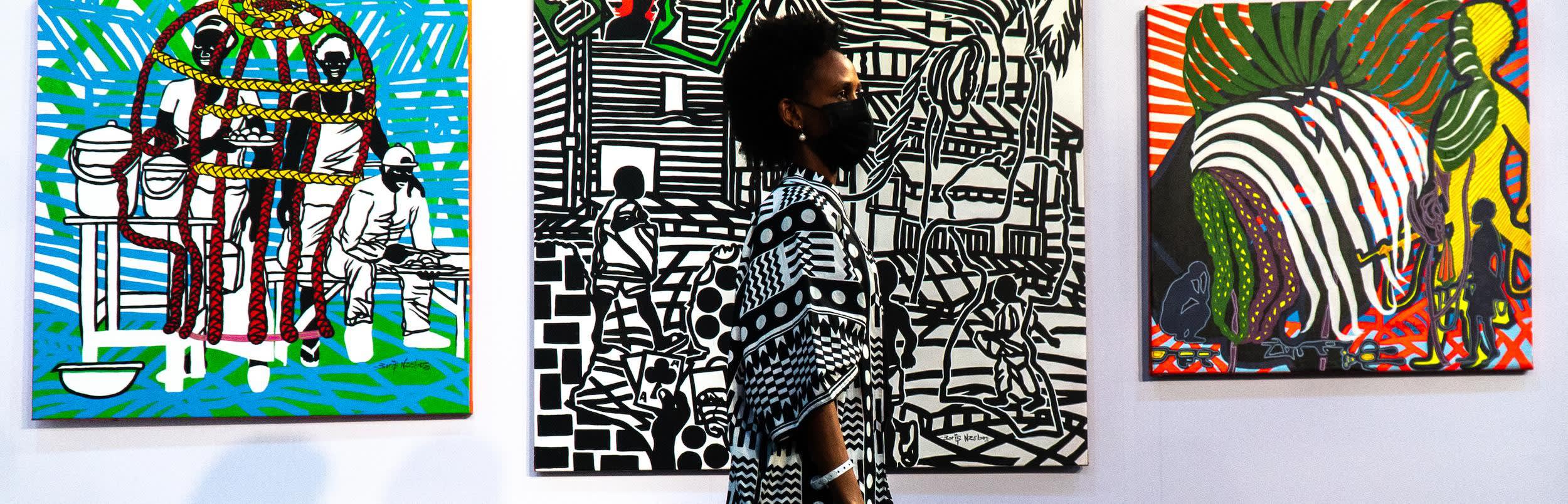 femme masquee admirant des oeuvres d'art africaine contemporaines a la foir d'art Art X Lagos