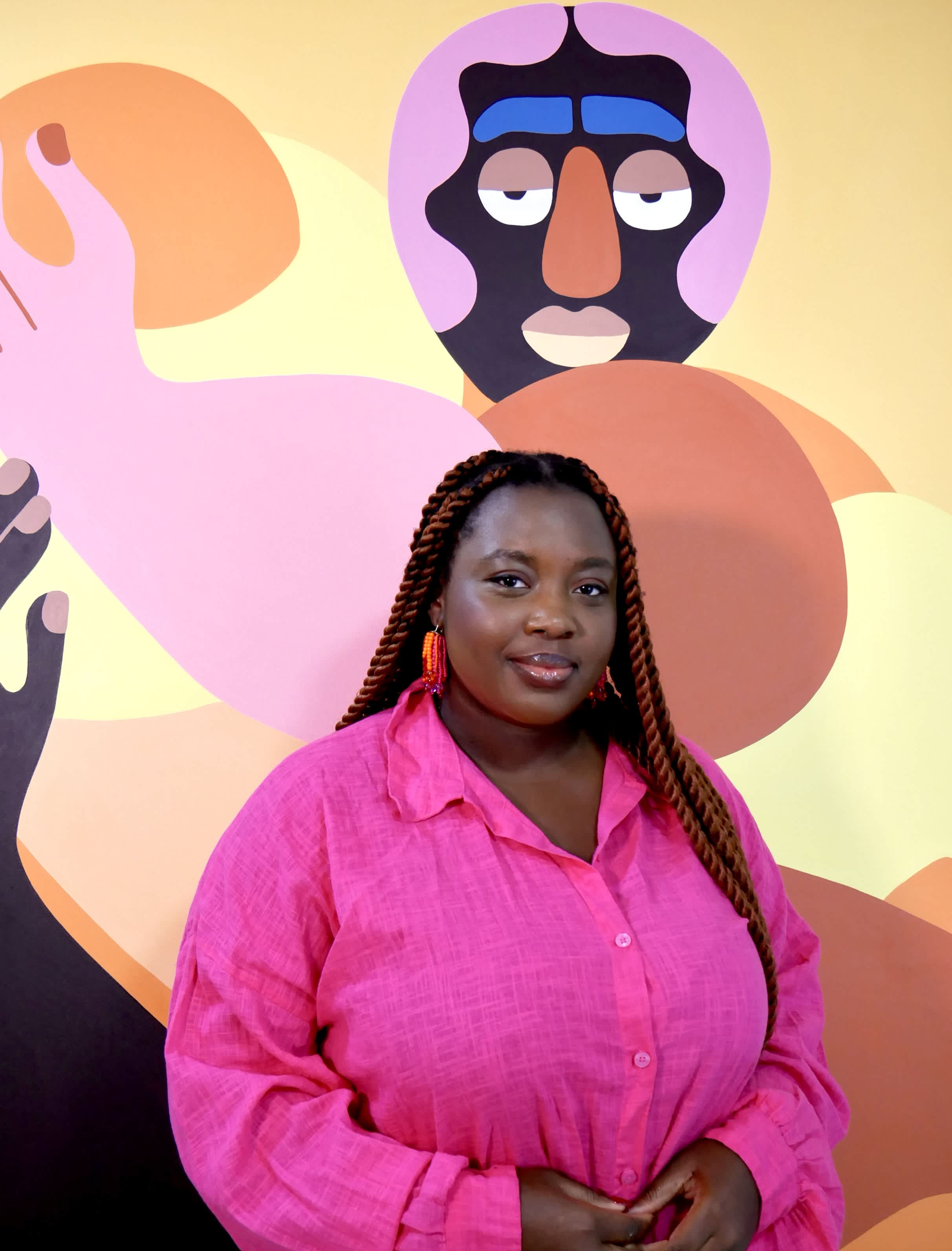One of the most exciting young female painters of this era, Deborah Segun’s art hangs on the wall behind her in her studio.