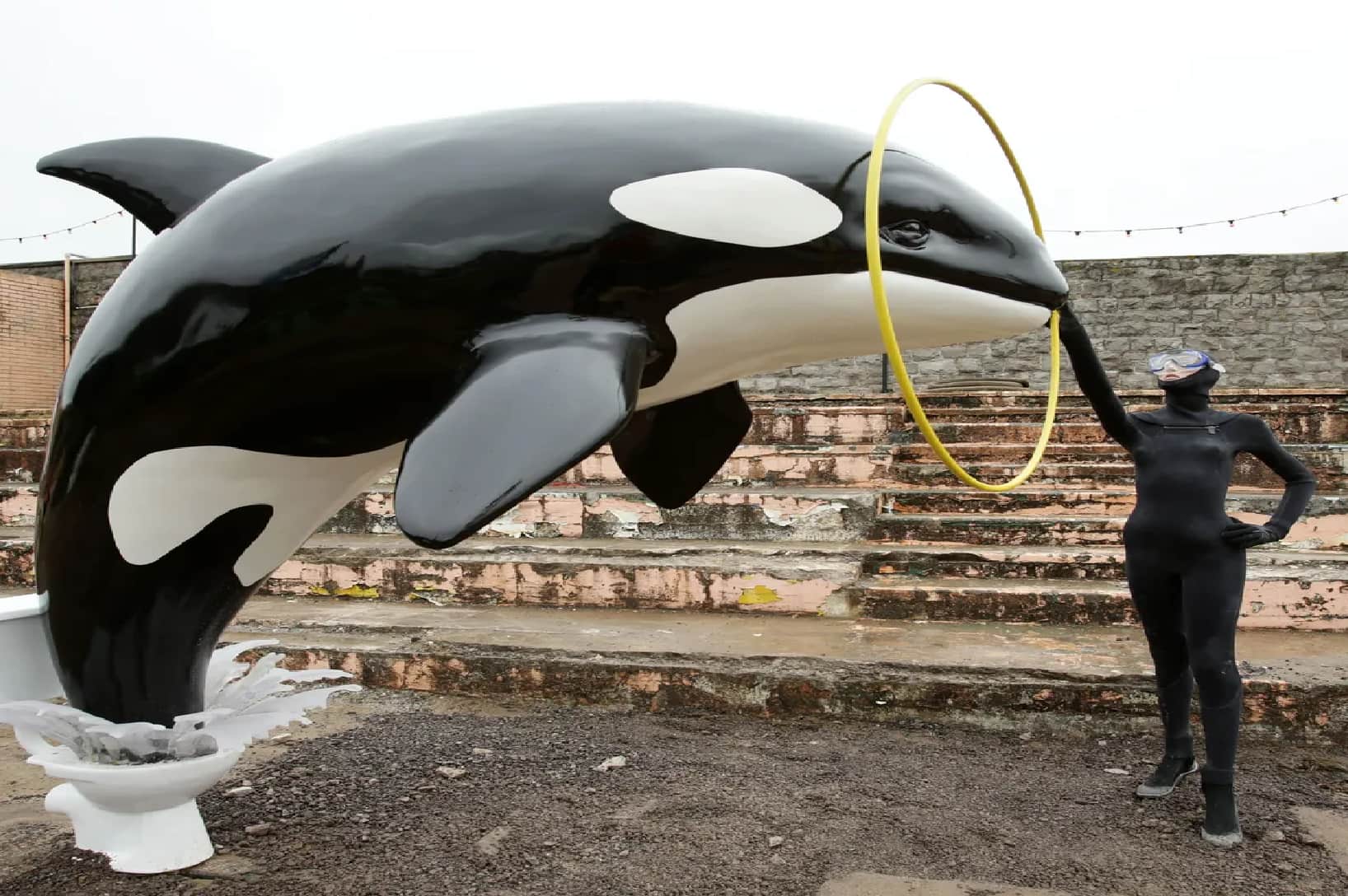 A large sculpture of an orca emerges from a toilet bowl, and jumps through a scuba diver’s hoop, raising questions as to the particular Dismaland meaning of this art piece.