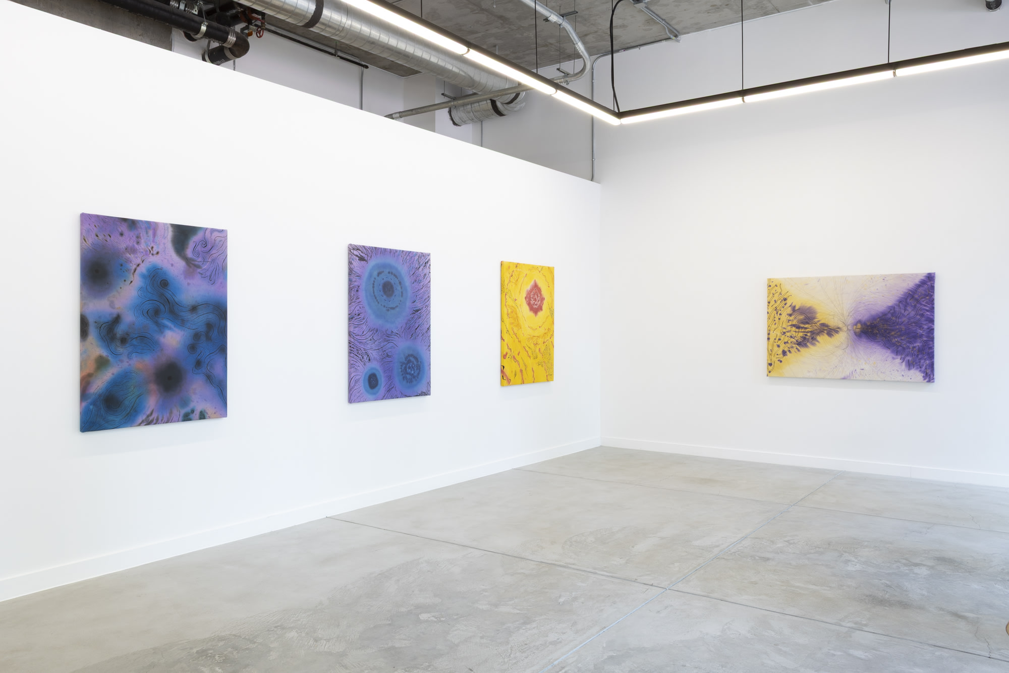 Bright gallery wall displays colorful abstract paintings in shades of blue, purple, and yellow.