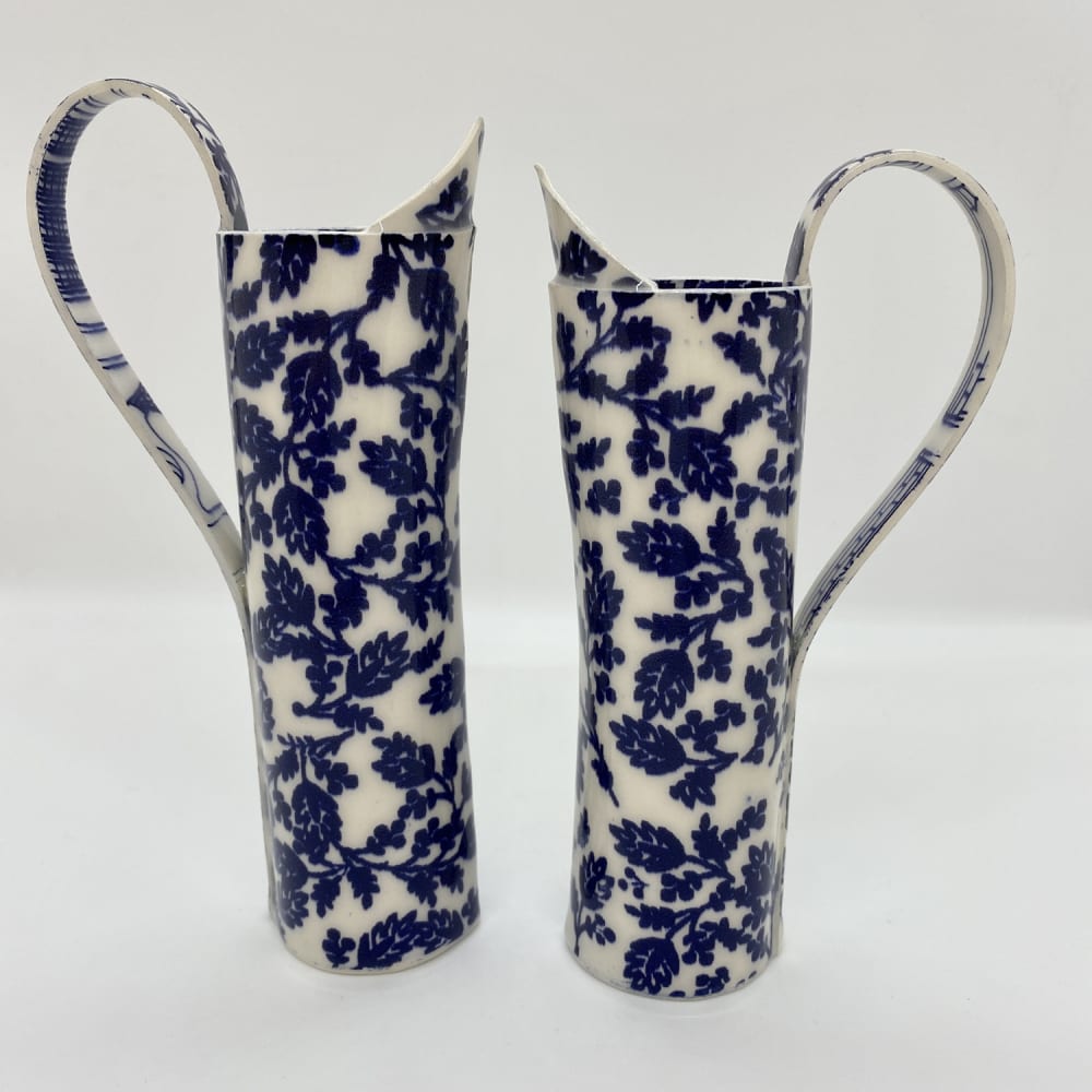 Janine Roper, two Ceramic Jugs in China White with a royal blue flower design standing facing each other.