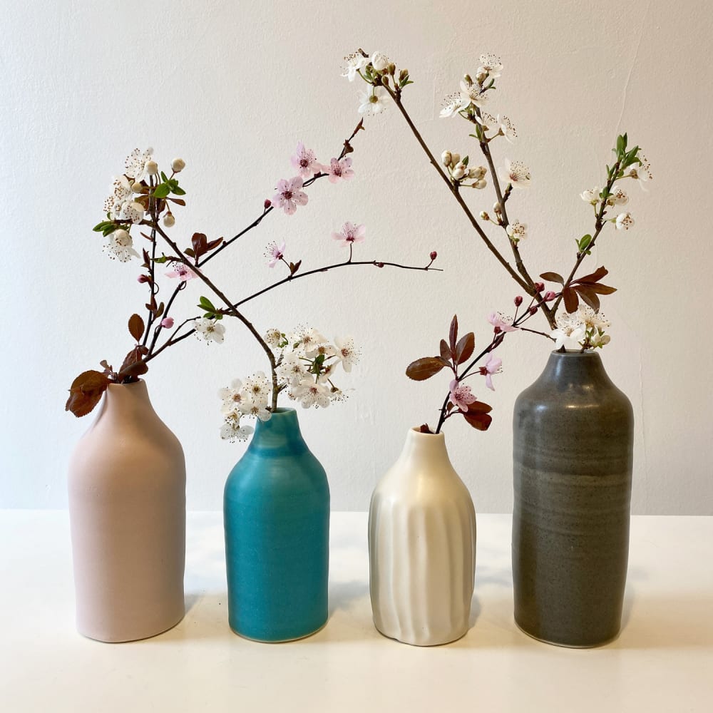 Linda Bloomfield range of ceramic bottles stood in line next to one another, steams of blossom occupy them