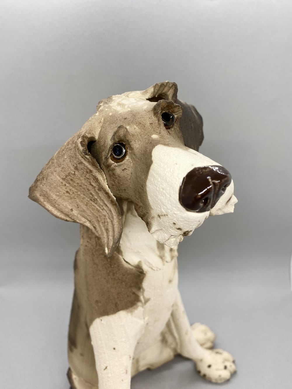 Virginia Dowe Edwards Raku smoked ceramic sculpture of a seated scruffy dog with a white tummy
