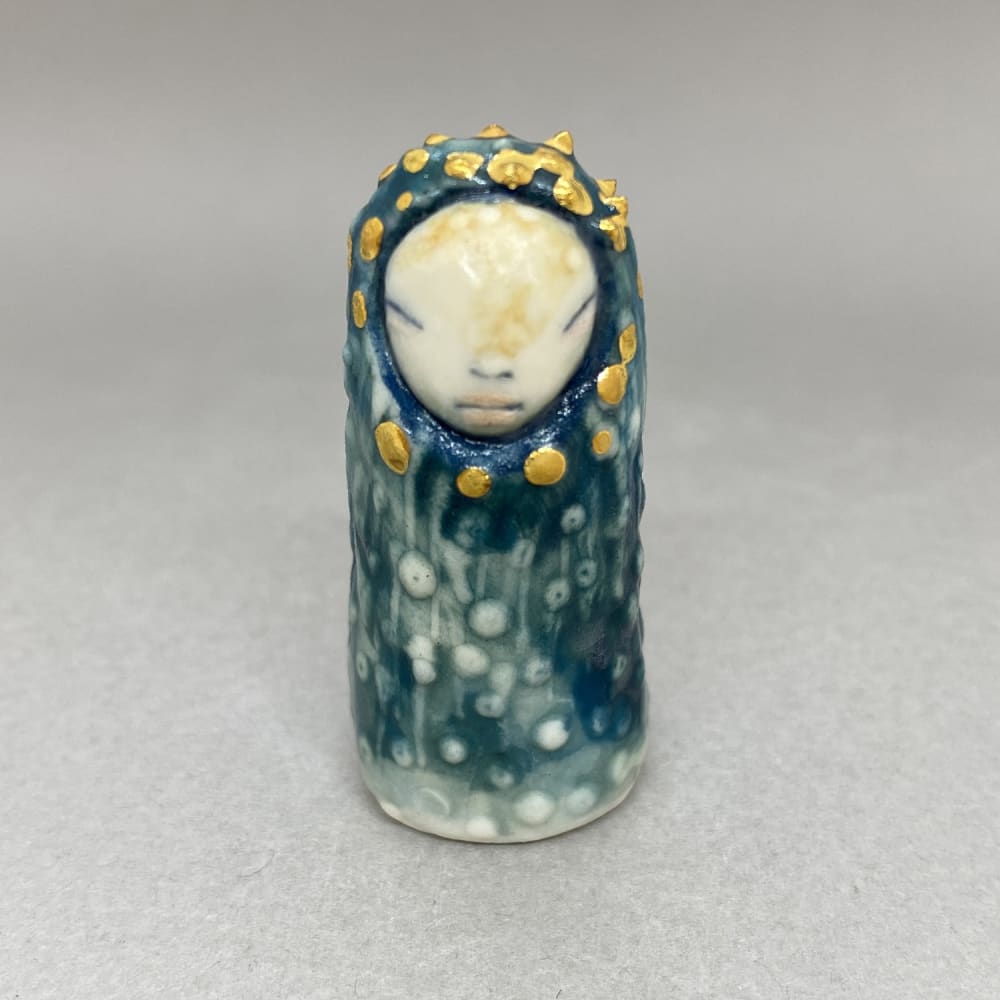 Marina Bauguil tiny sculpture inspired by Japanese kami culture in blue with gold droplets around its face.