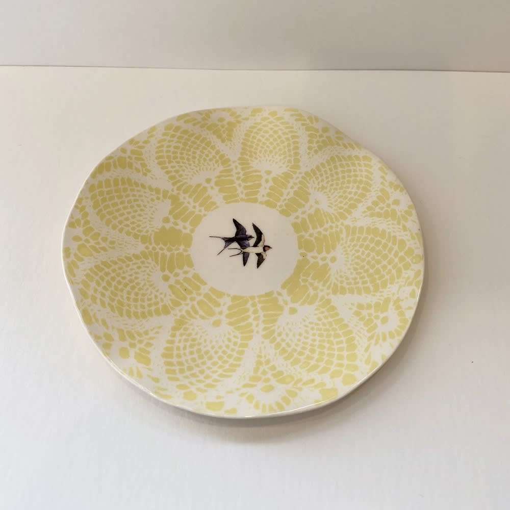Fliff Carr white ceramic plate with yellow lace detail printed around it and 2 swallows printed in the centre.