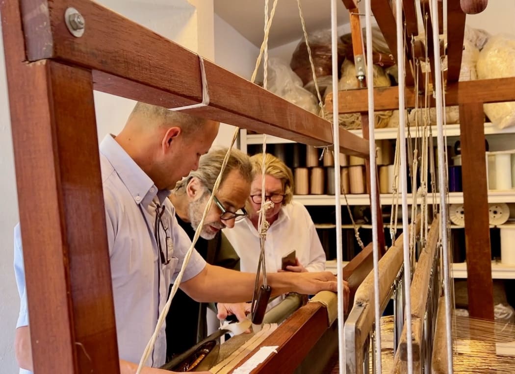 Luis Luna and Monica de Rhodes observe the details of the artwork as it is being woven.