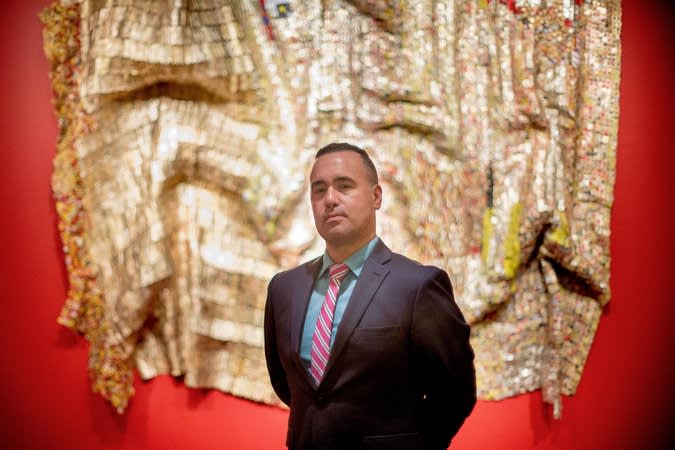 Kevin Dumouchelle with an untitled 2009 work by El Anatsui at the Smithsonian Museum of African Art in Washington. Image courtesy of Gabriella Demczuk for The New York Times.