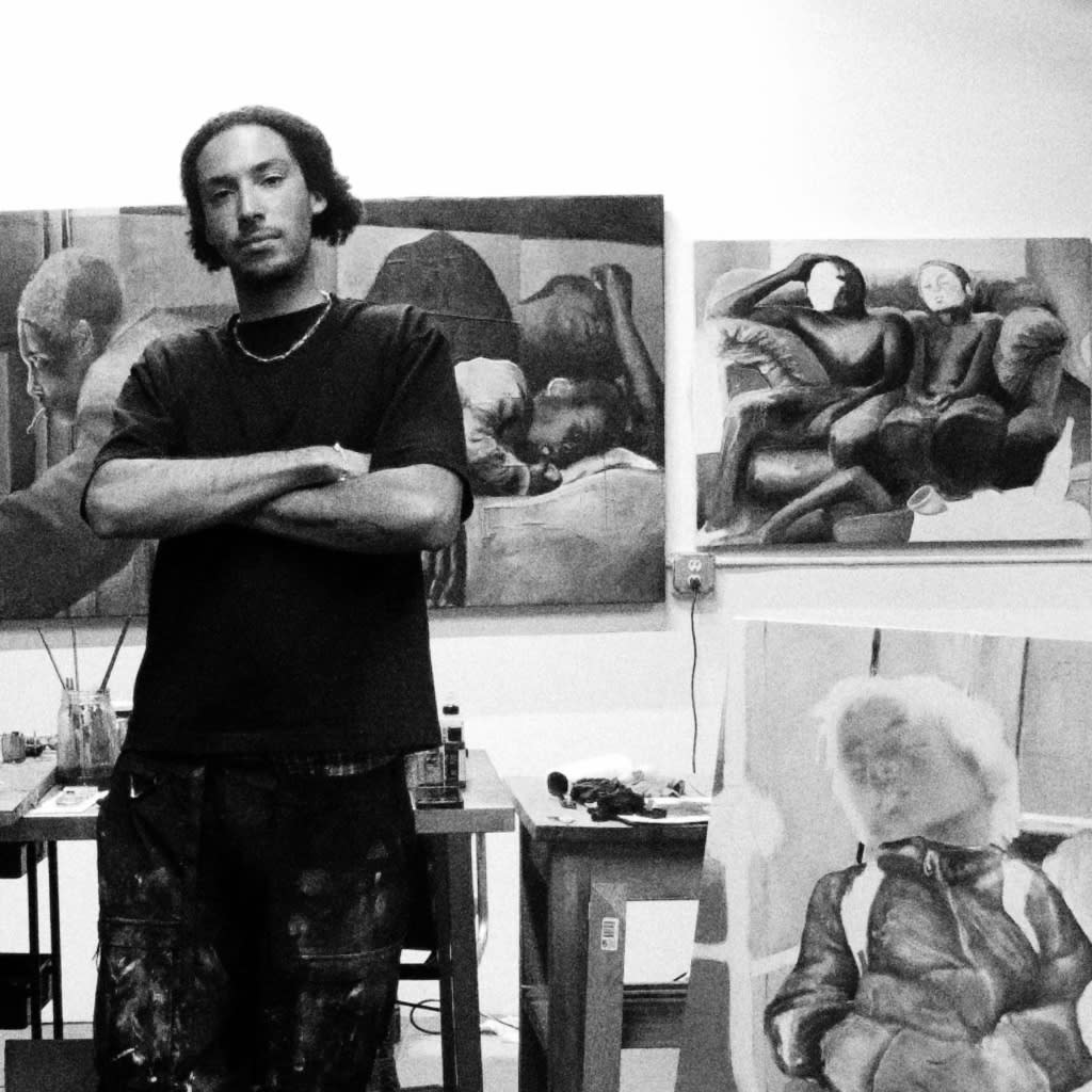 black and white photo of the artist standing in his studio with paintings in the background