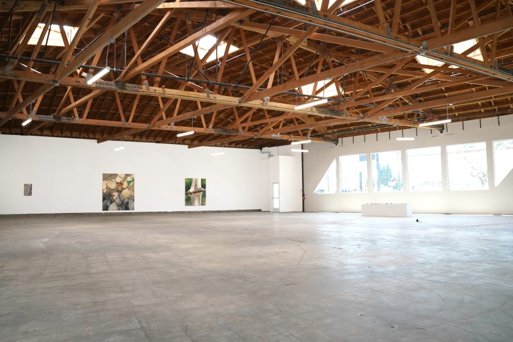 photograph of the gallery with paintings on the walls and a crowd of people inside