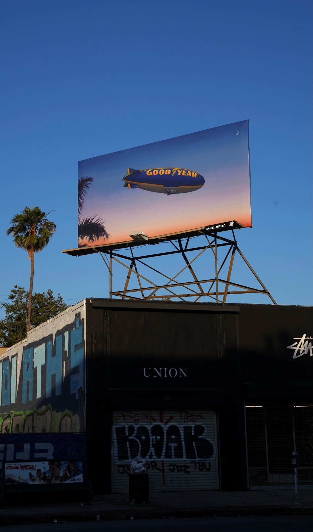 photo of a billboard by daniel antelo - goodyear blimp flying in the sky