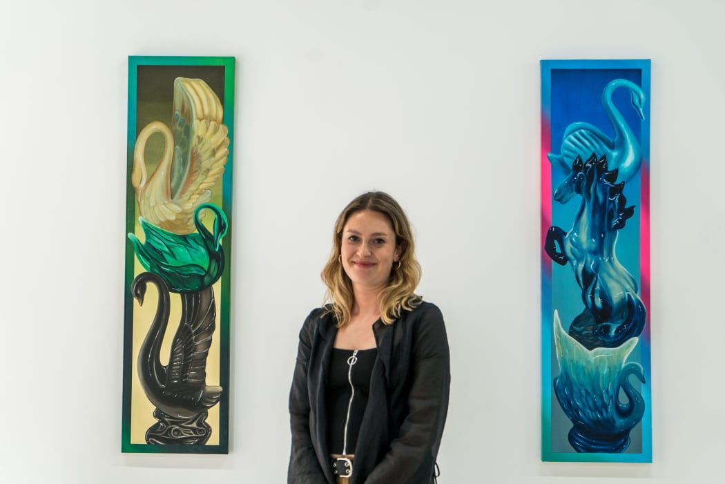 photo of Vanessa Indies in front of two artworks by Douglas de Souza
